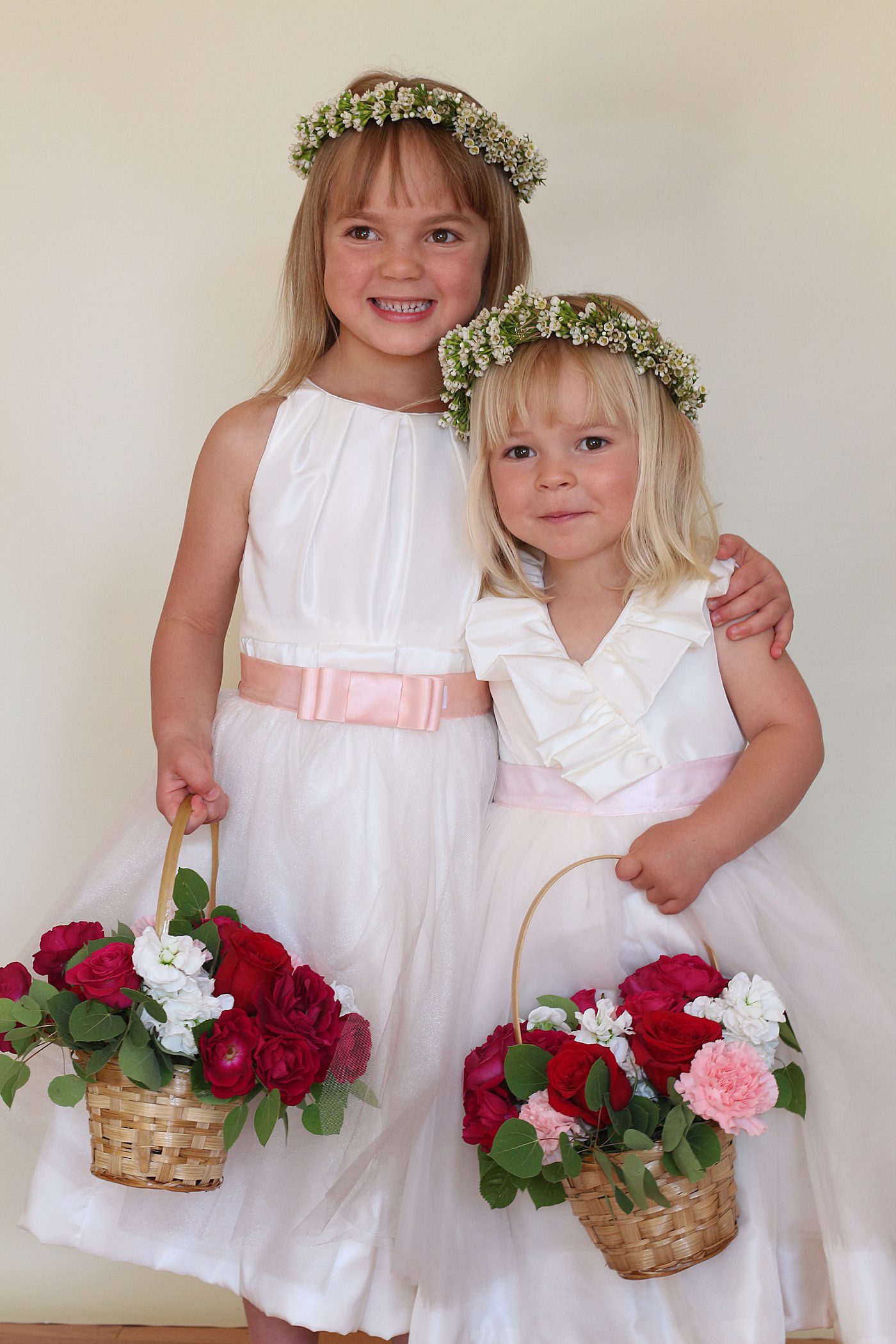 two flower girls smiling holding baskets of flowers