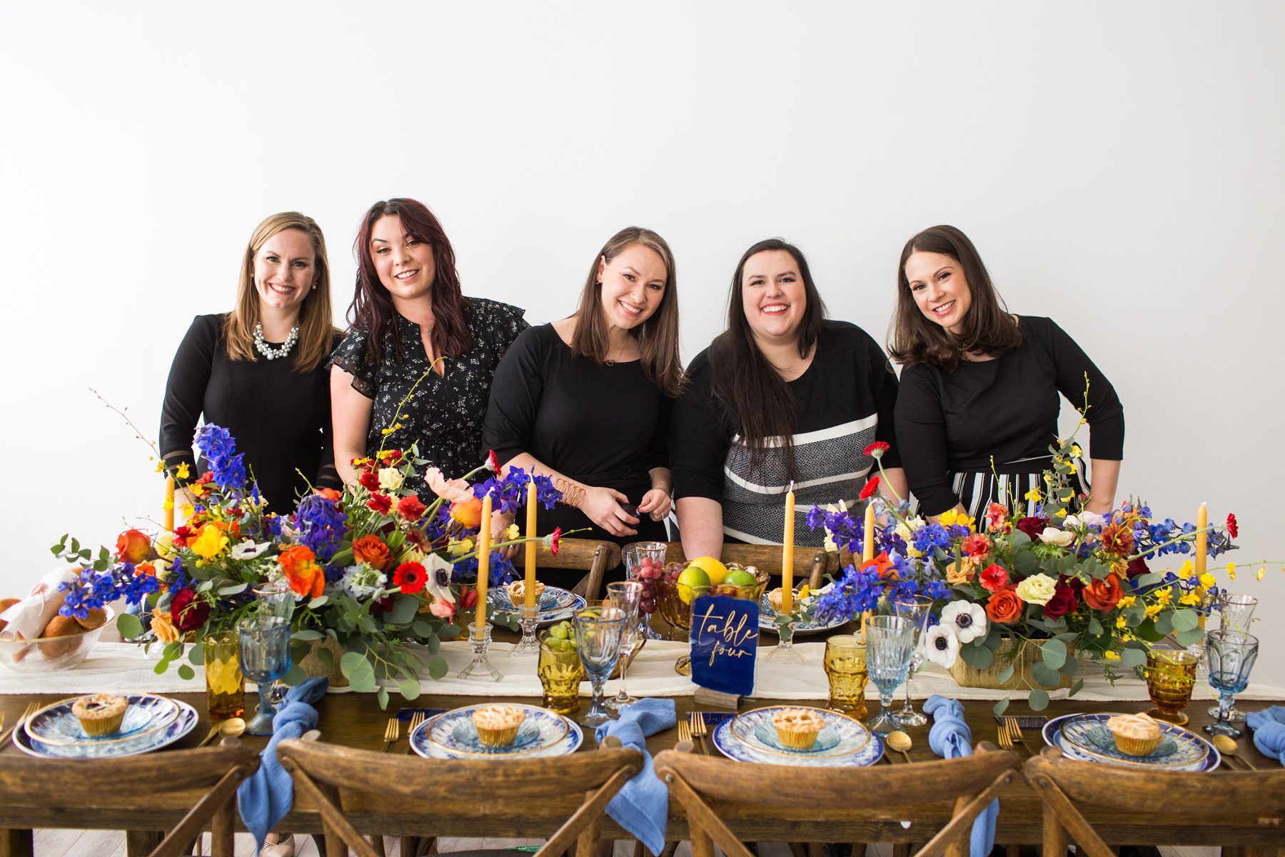 five women at a beautifully set dinner table with colorful florals