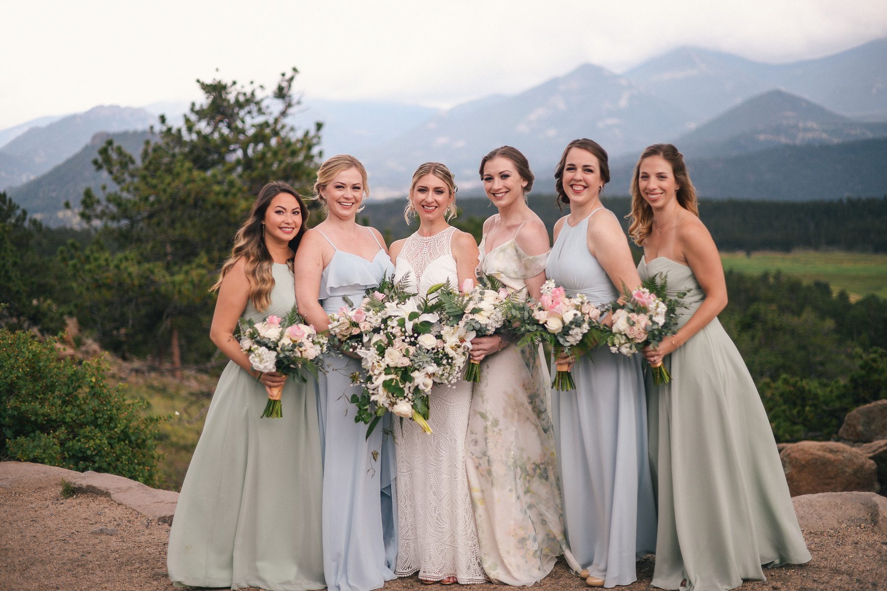 bridal party wearing dusty blue and dusty green dresses with blush flowers