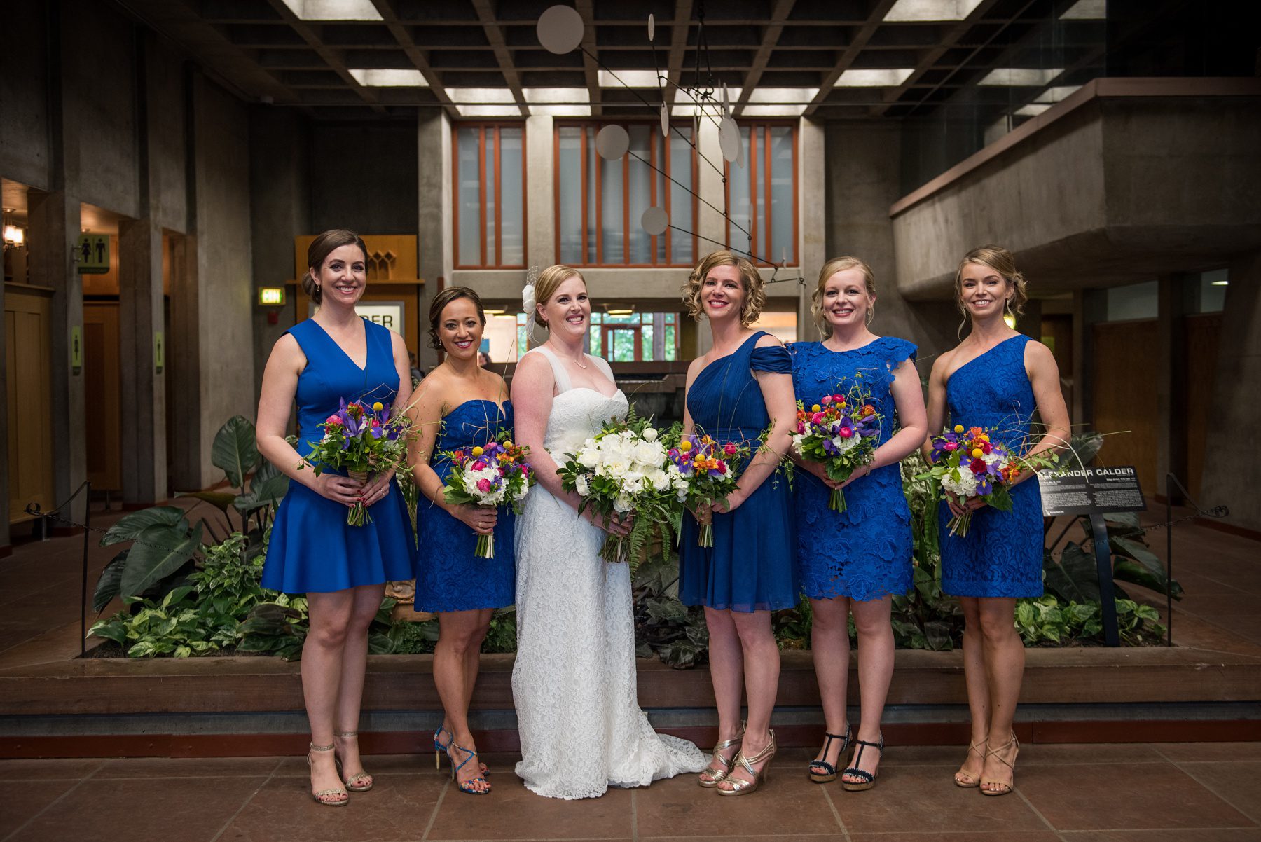 bridesmaids in blue dresses with colorful bouquets