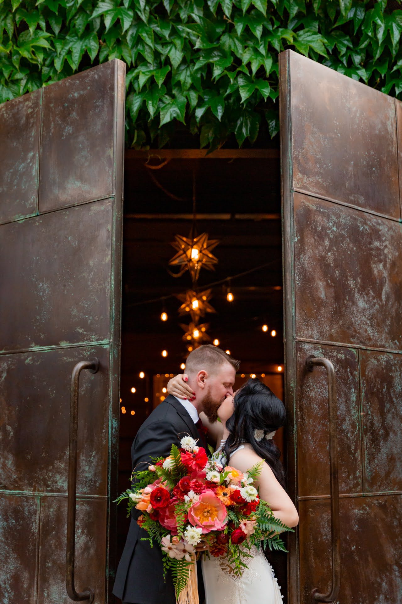bride and groom kissing holding a red bouquet
