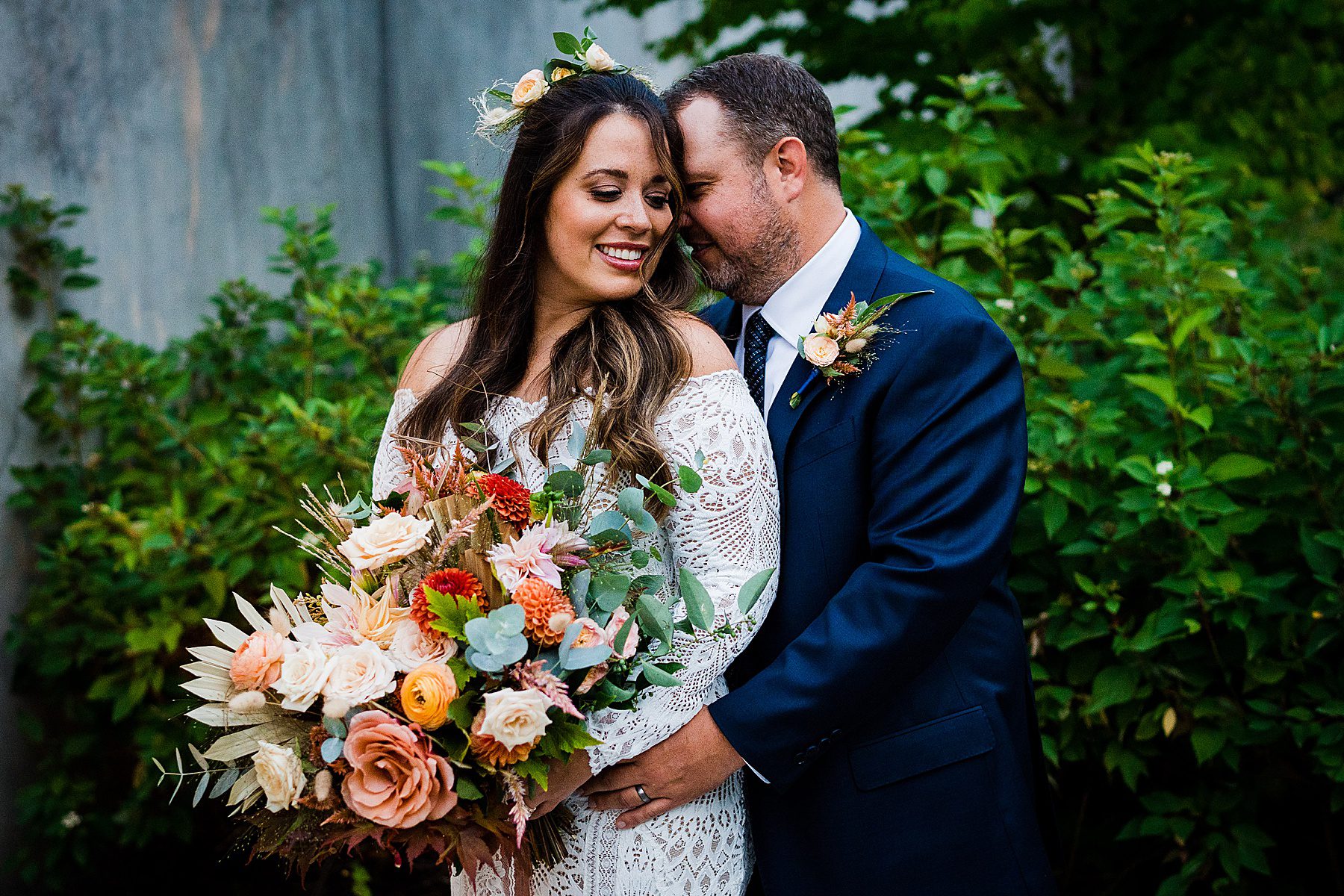 a groom holding a bride carrying a colorful bouquet