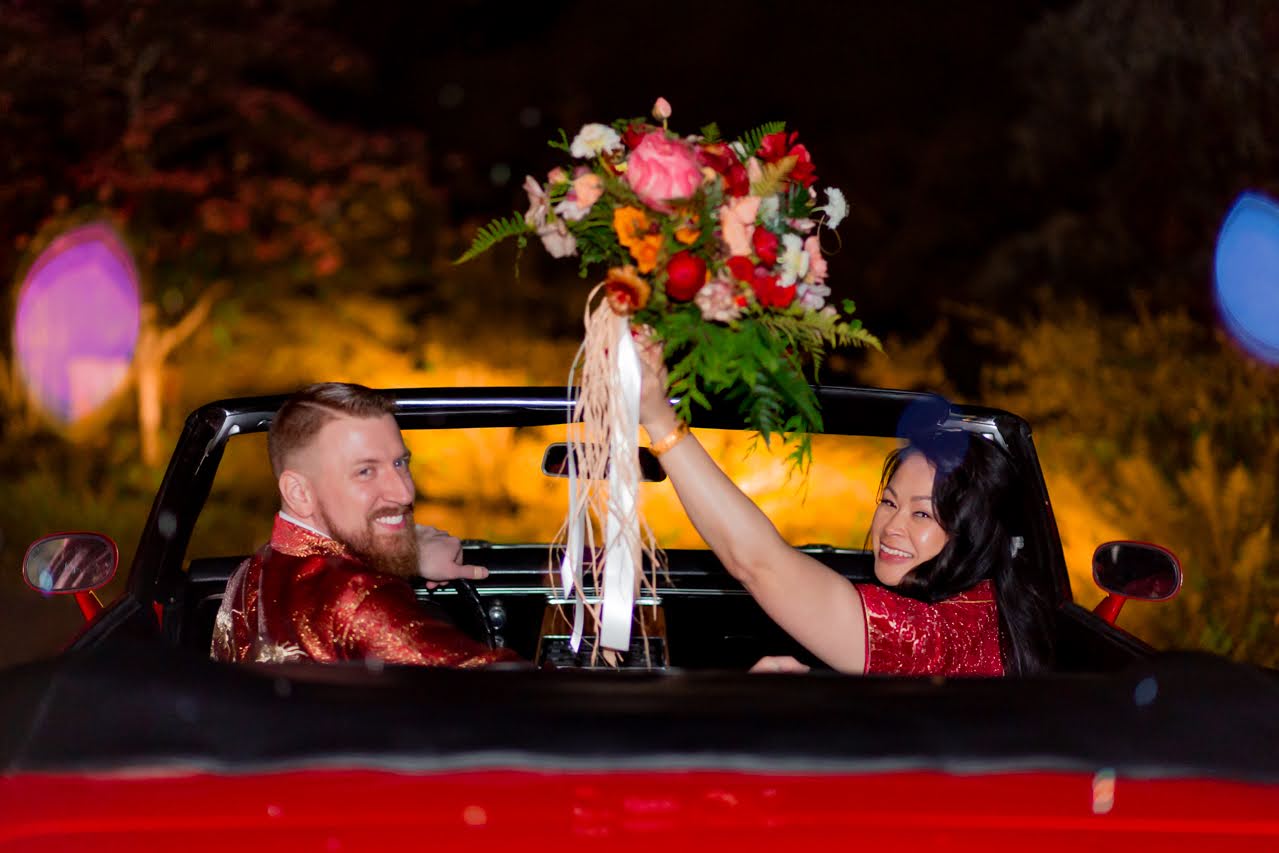 bride and groom in a red convertible