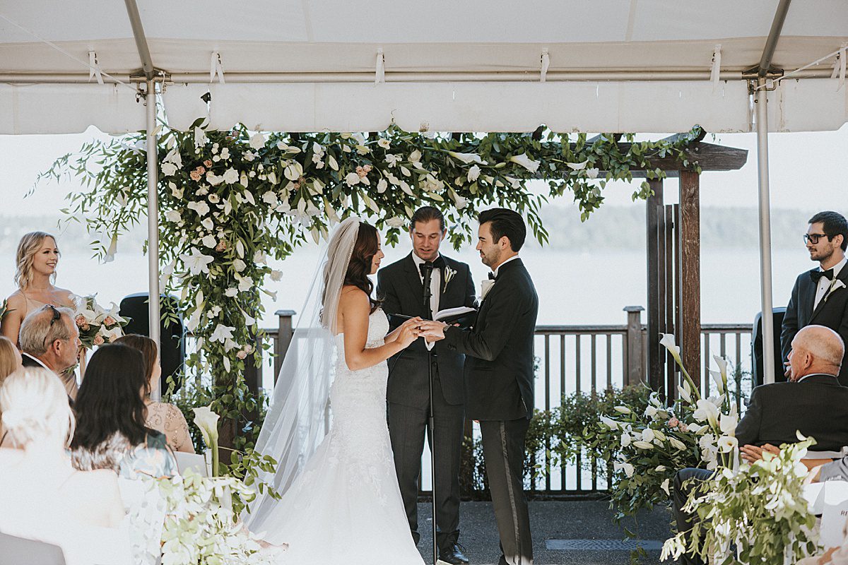 a bride and groom exchanging vows in front of a floral backdrop