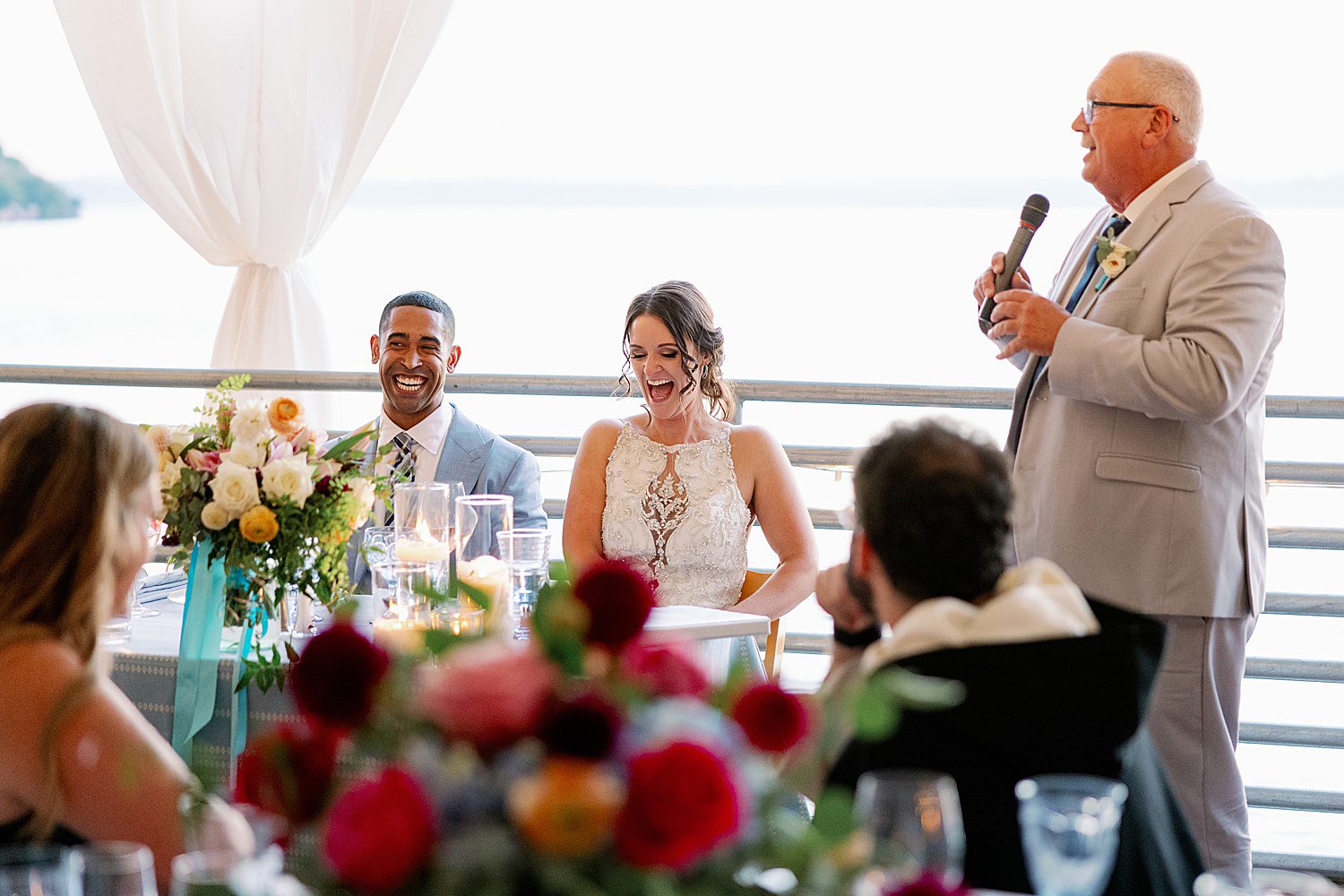 a father give a speech at a wedding in front of the bride and groom