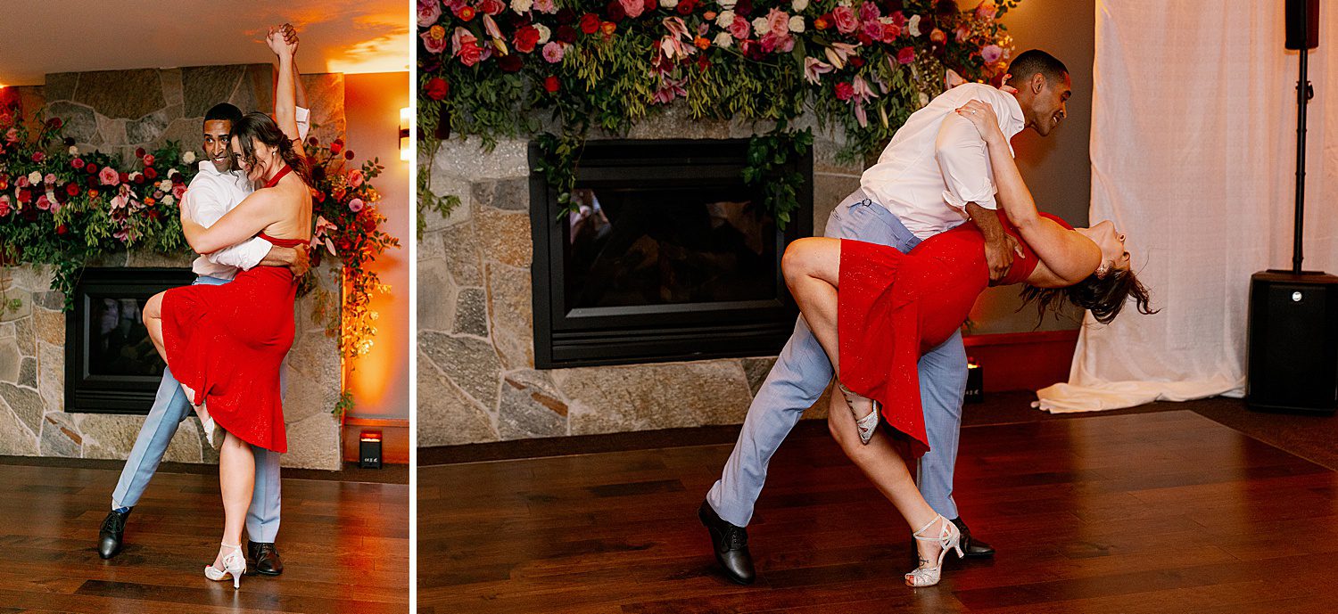 a man dips a woman in a red dress in front of a mantle floral installation