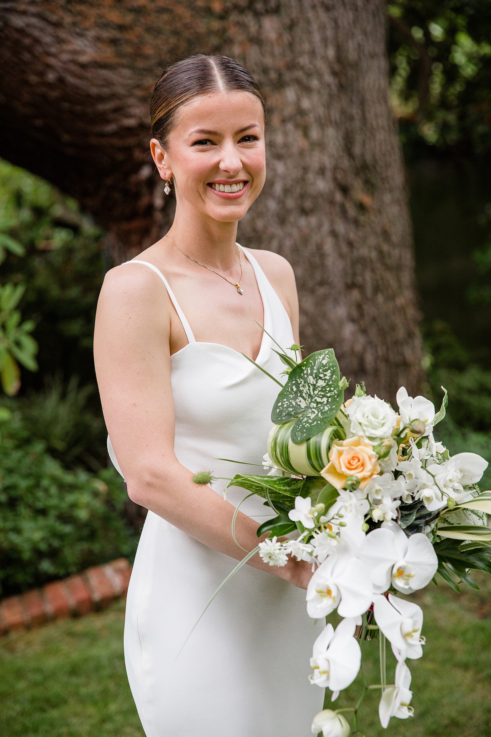 a bride in a modern wedding dress holds a green and white modern bridal bouquet