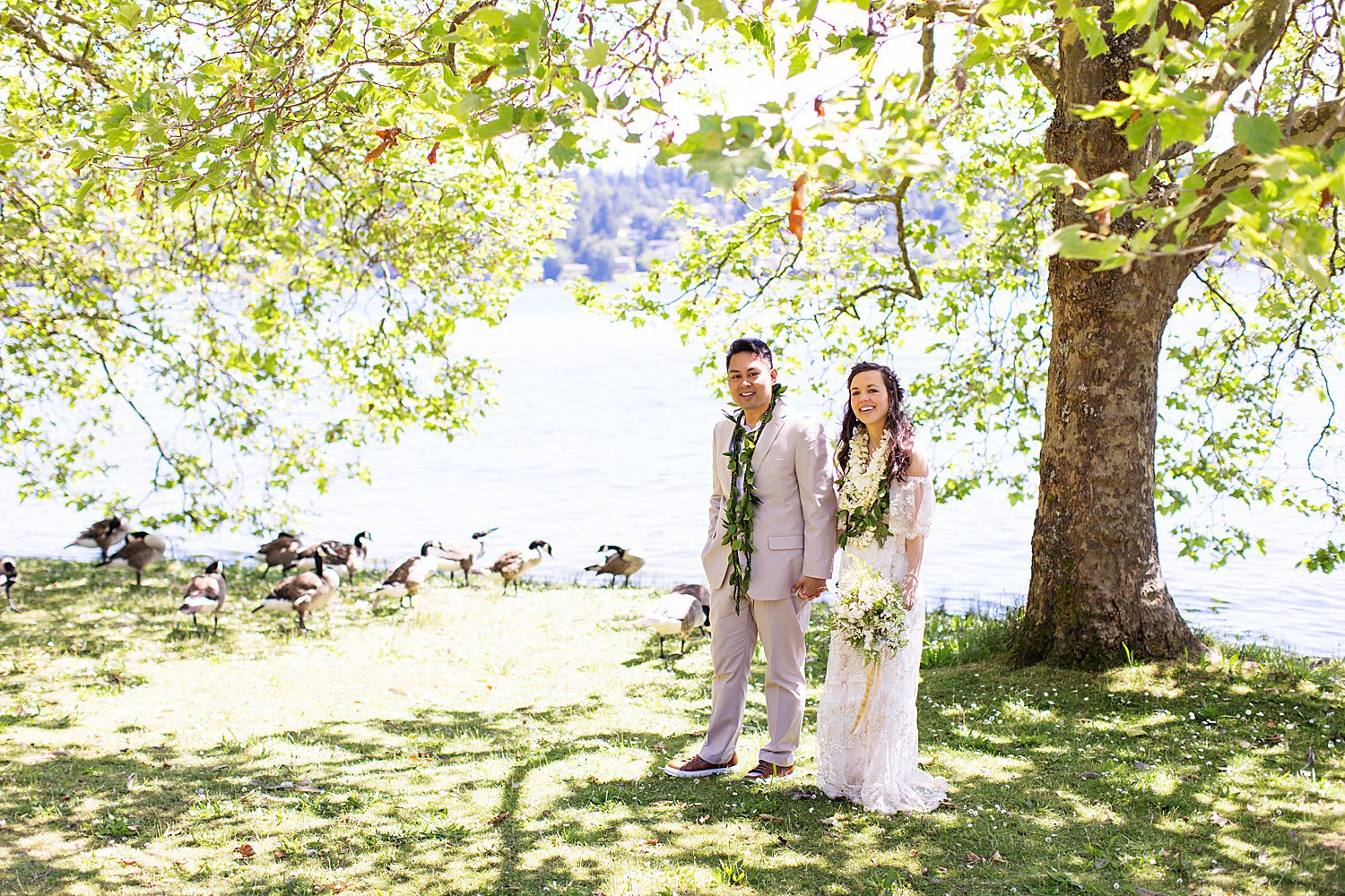 a bride and groom stand by the lake at Seward Park in Seattle