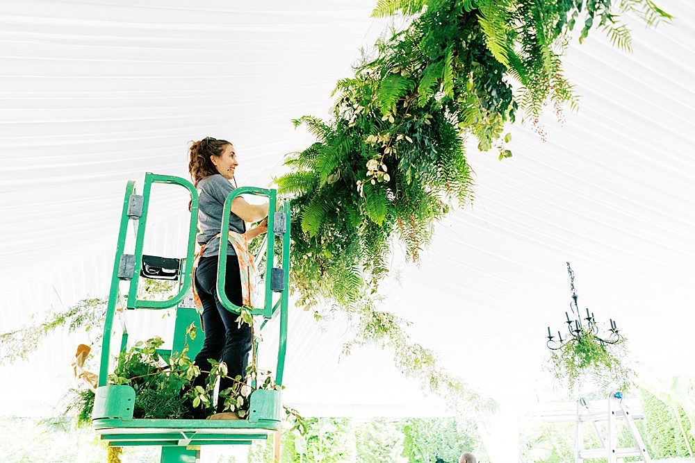 florist on scissors lift hanging greenery