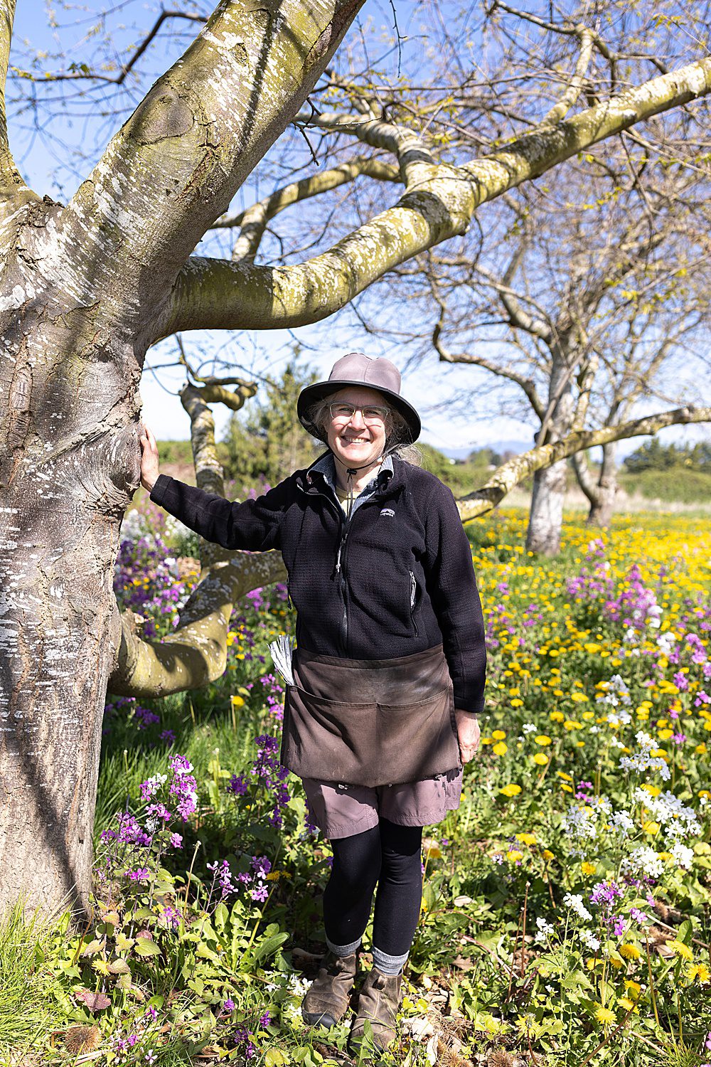 a woman stands next to a tree