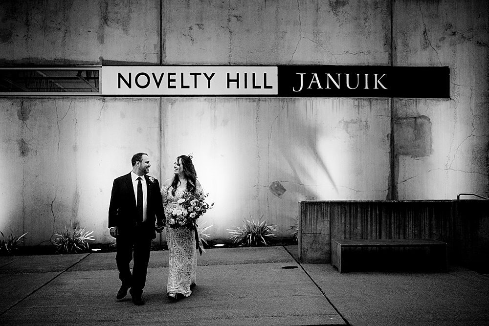 a bride and groom stand by the Novelty-Hill Januik sign