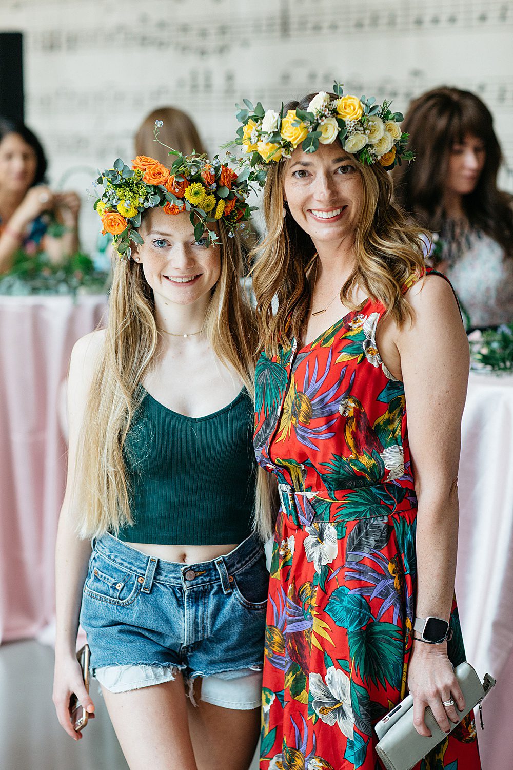 a woman in a dress with a teenage daughter wear flower crowns