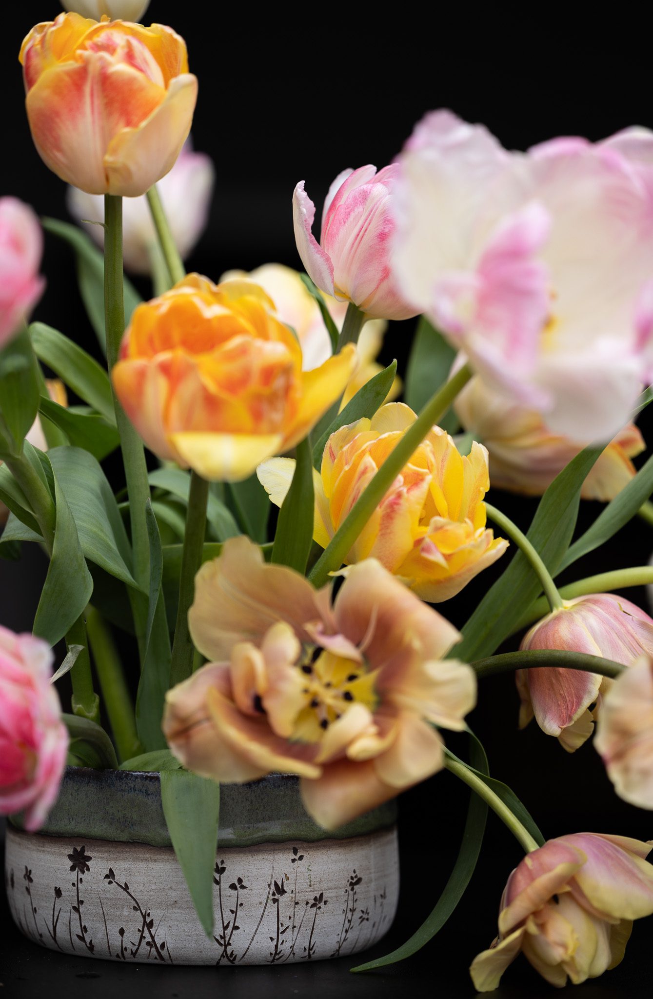 pink, brown, and orange tulips in a ceramic vase
