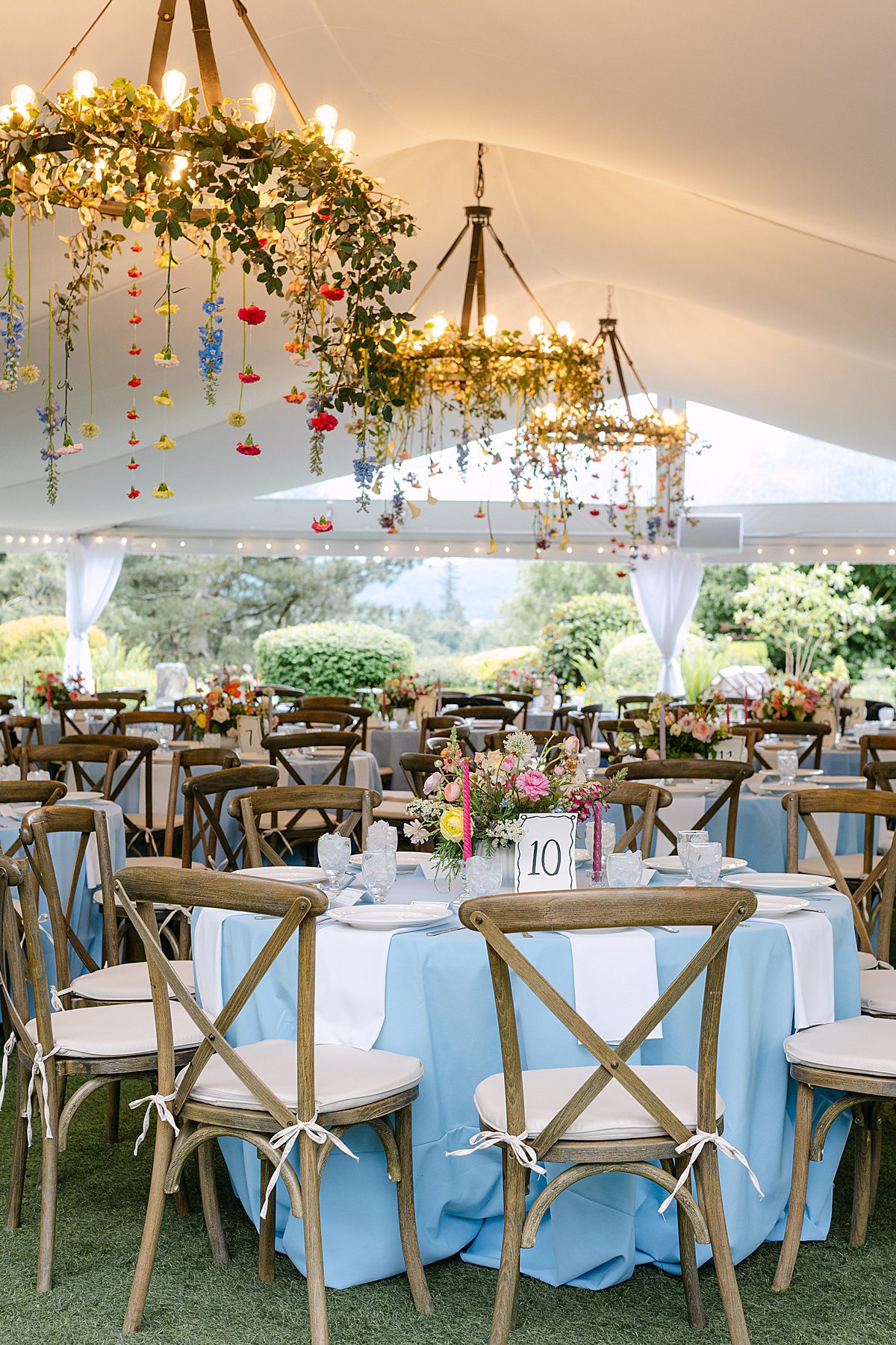flowers and greenery hanging from wedding tent chandeliers
